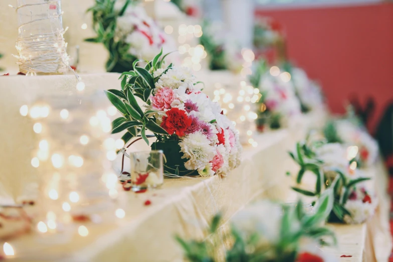 a table that has a bunch of flowers on it, pexels, romanticism, fairy lights, red and white, wedding, low detailed