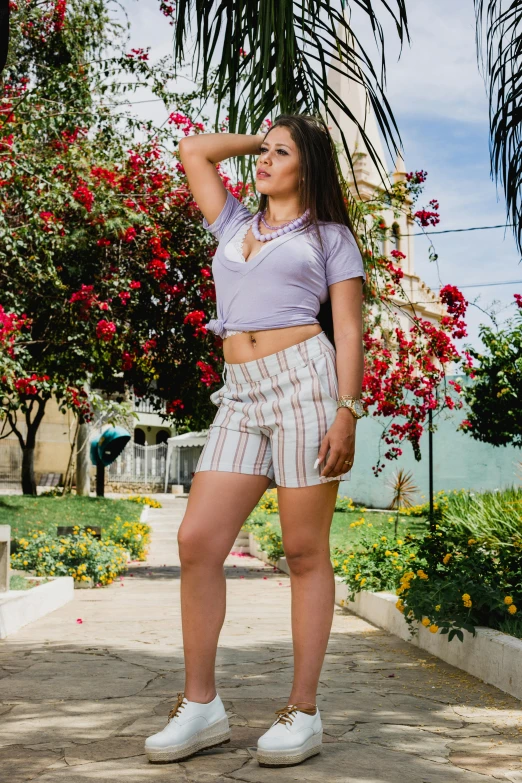 a woman standing in front of a palm tree, a colorized photo, unsplash, wearing golf shorts, latina, lilac, striped