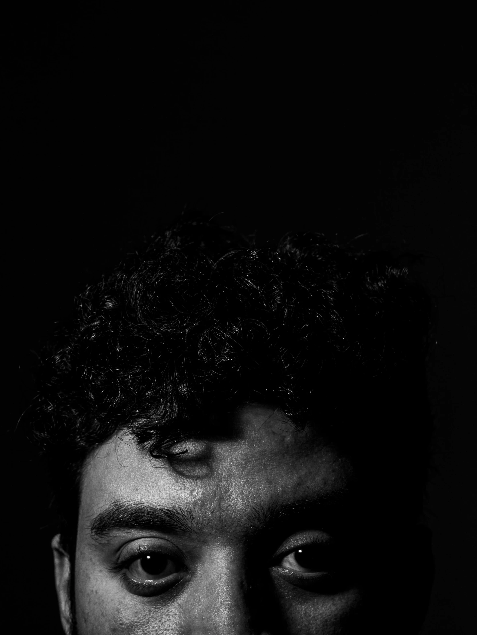 a black and white photo of a man with curly hair, a character portrait, by Alexis Grimou, large black eyes!!!, jordan lamarre - wan, riyahd cassiem, dark and scary