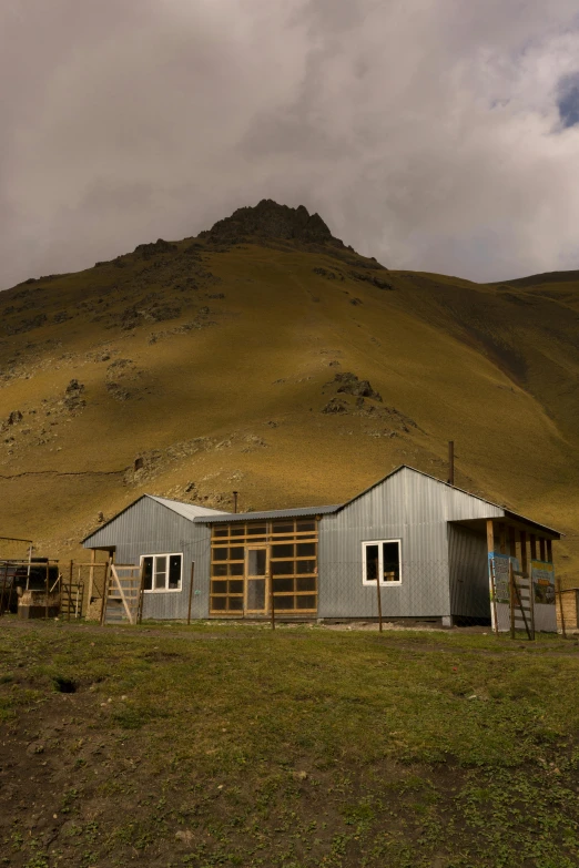 a house in the middle of a field with a mountain in the background, neo - andean architecture, 10k, shed, frontview