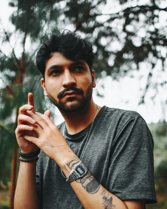 a man with a tattoo on his arm smokes a cigarette, an album cover, by Alejandro Obregón, trending on unsplash, provocative indian, non binary model, mark edward fischbach, youtuber