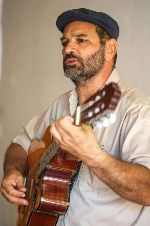 a man with a hat playing a guitar, ahmad merheb, looking across the shoulder, photograph