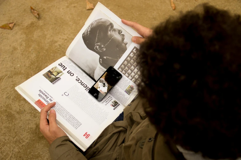 a person sitting on the ground reading a book, by Daniel Lieske, happening, scanning items with smartphone, helio oiticica, close up portrait shot, african arts magazine