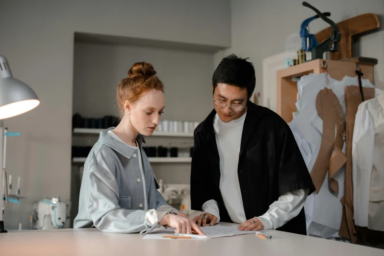 a man and a woman looking at a piece of paper, a drawing, pexels contest winner, academic clothing, modeling studio, gif, nursing