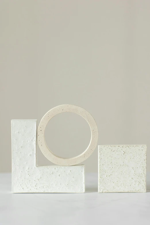 a white object sitting on top of a table, an abstract sculpture, inspired by Isamu Noguchi, concrete art, rings, square, edge vignette, various sizes