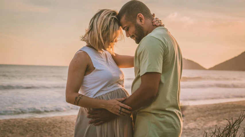 a man and woman standing next to each other on a beach, pexels contest winner, happening, maternity feeling, avatar image, hispanic, soft warm light