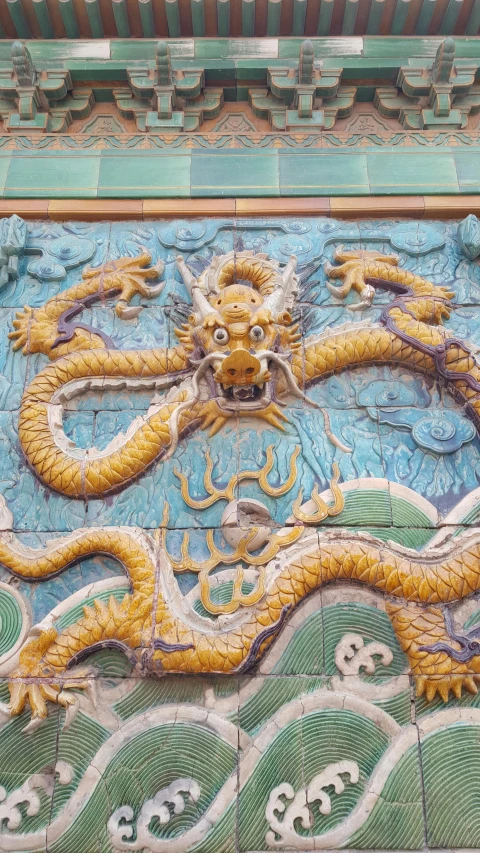 a close up of a dragon on a building, gold and teal color scheme, qing dynasty, tiled, on a large marble wall