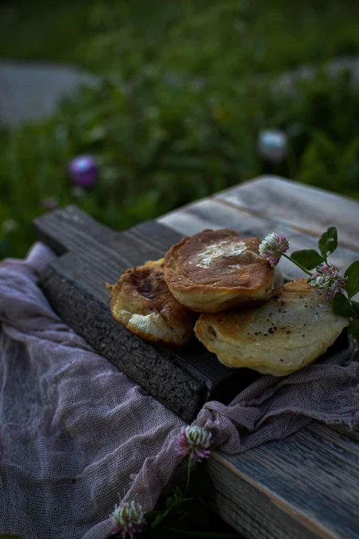 a piece of bread sitting on top of a wooden table, a still life, unsplash, romanticism, crispy buns, herbs and flowers, portrait image