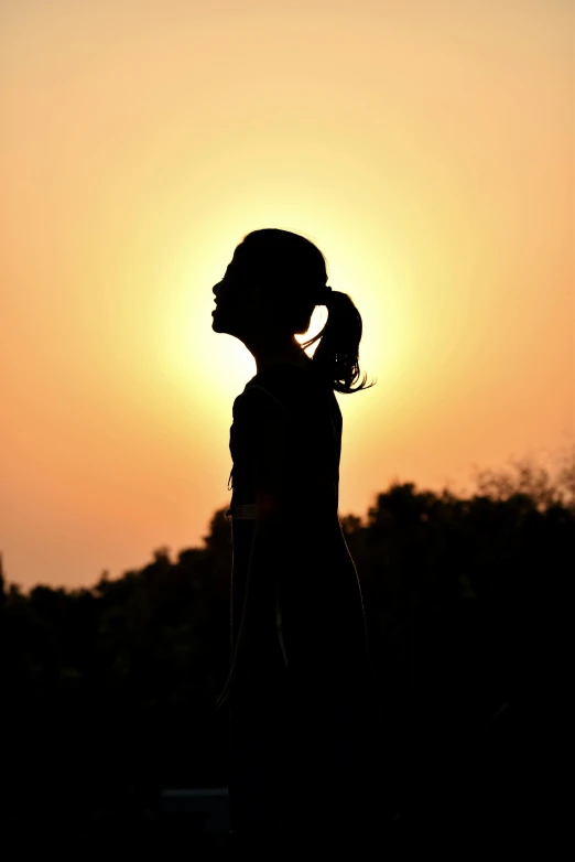 a silhouette of a woman standing in front of a sunset, a woman's profile, sports photo, taken in the late 2010s, ((sunset))