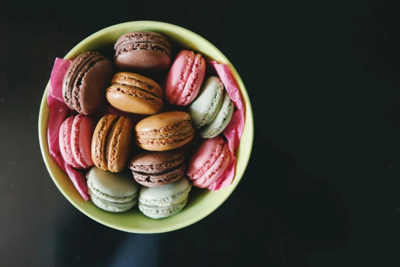 a green bowl filled with macarons on top of a table, a pastel, pexels contest winner, brown and magenta color scheme, thumbnail, red and brown color scheme, high - contrast