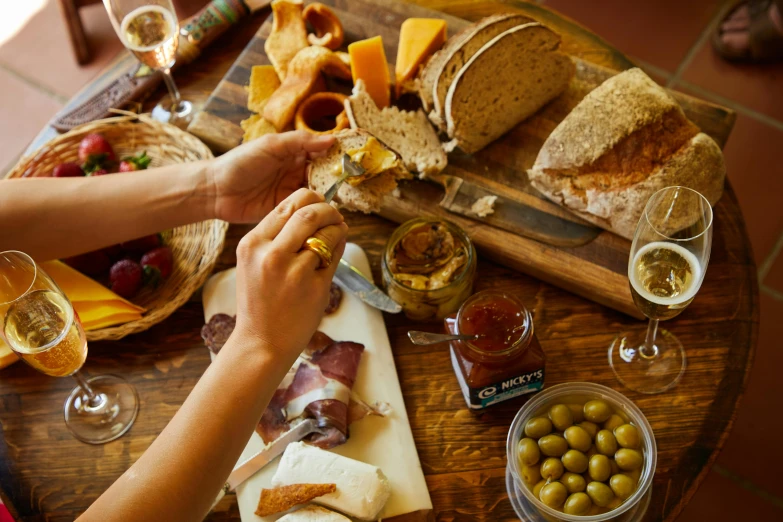 a couple of people that are sitting at a table, eating a cheese platter, wide overhead shot, well preserved, harvest