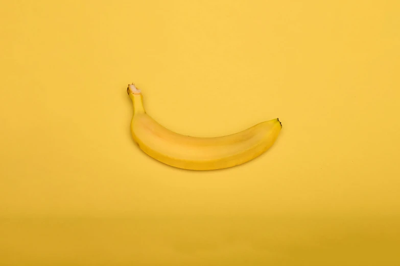 a banana sitting on top of a yellow surface, ignant, made of food, shot with sony alpha 1 camera, grey