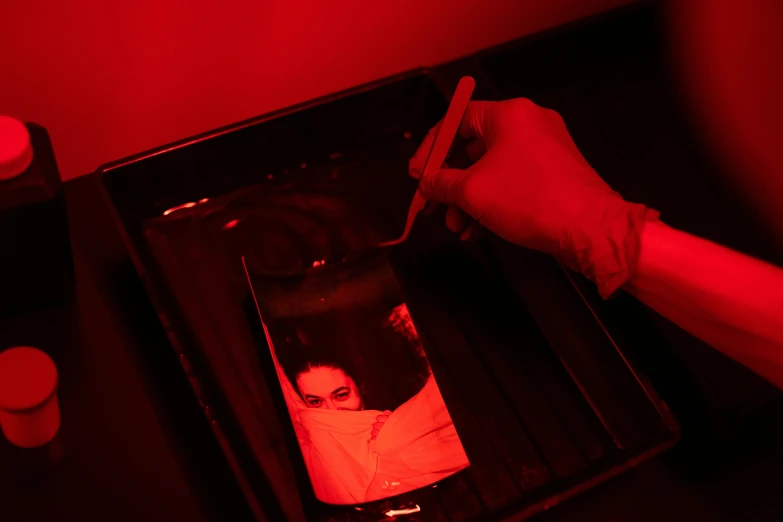 a red light illuminates a picture of a woman, a silk screen, experiment in laboratory, in a red dish, spooky photo, press shot