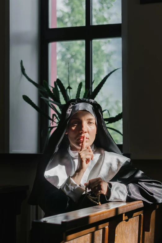 a woman dressed as a nun praying in a church, an album cover, inspired by Sofonisba Anguissola, unsplash, sitting in dean's office, with a straw, middle finger, portrait of ((mischievous))