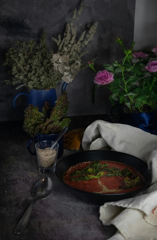 a bowl of soup sitting on top of a table, a still life, inspired by Henriette Grindat, renaissance, meat and lichens, vibrant dark mood, herbs and flowers, tomato sauce