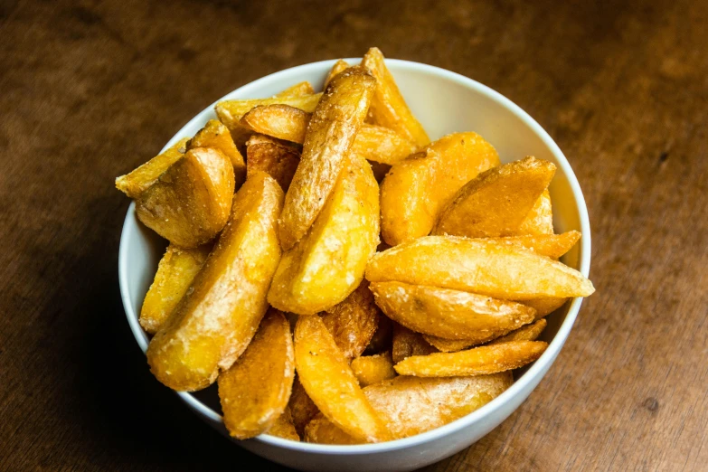 a bowl filled with french fries on top of a wooden table, skewed shot, thumbnail, potatoes, braavos