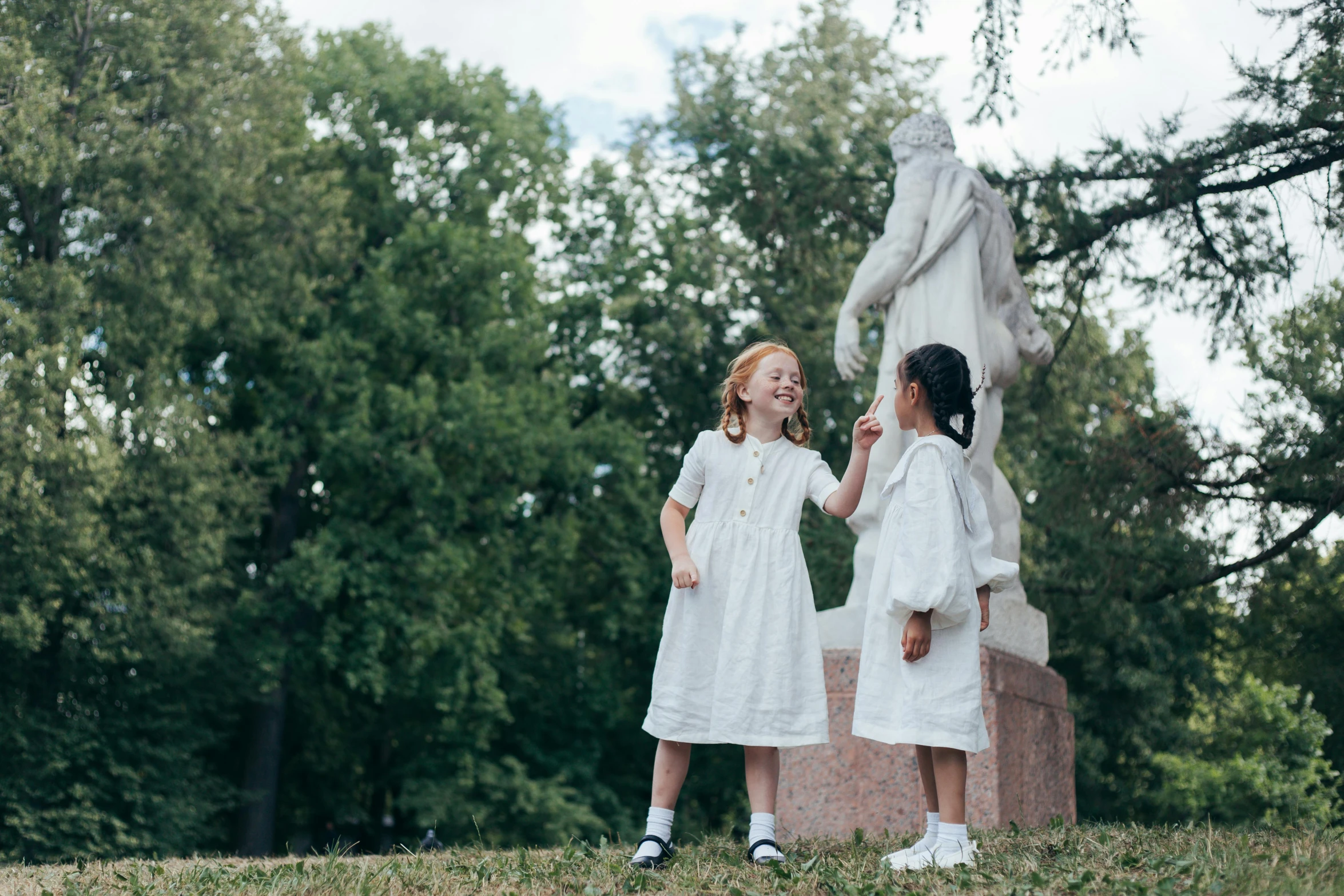 two little girls standing in front of a statue, inspired by Kate Greenaway, pexels contest winner, symbolism, white russian clothes, apollinaris vasnetsov, with subtitles, product introduction photo