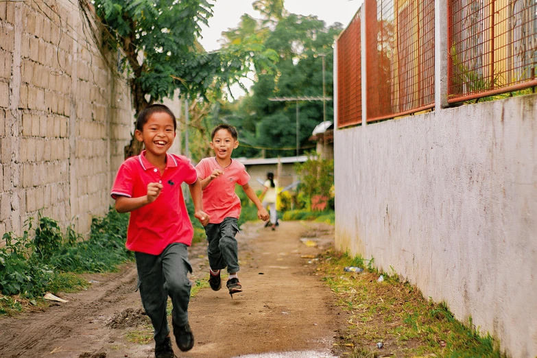 a couple of kids running down a dirt road, manila, smiling, educational, multiple stories