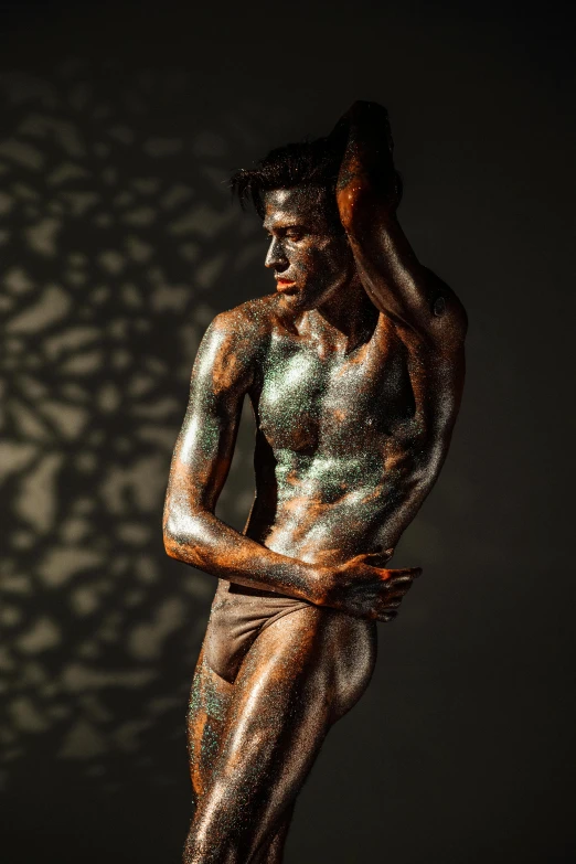 a statue of a man standing in front of a wall, featured on zbrush central, figurative art, body painted with black fluid, iridescent skin, dirty olive skin, trending photo