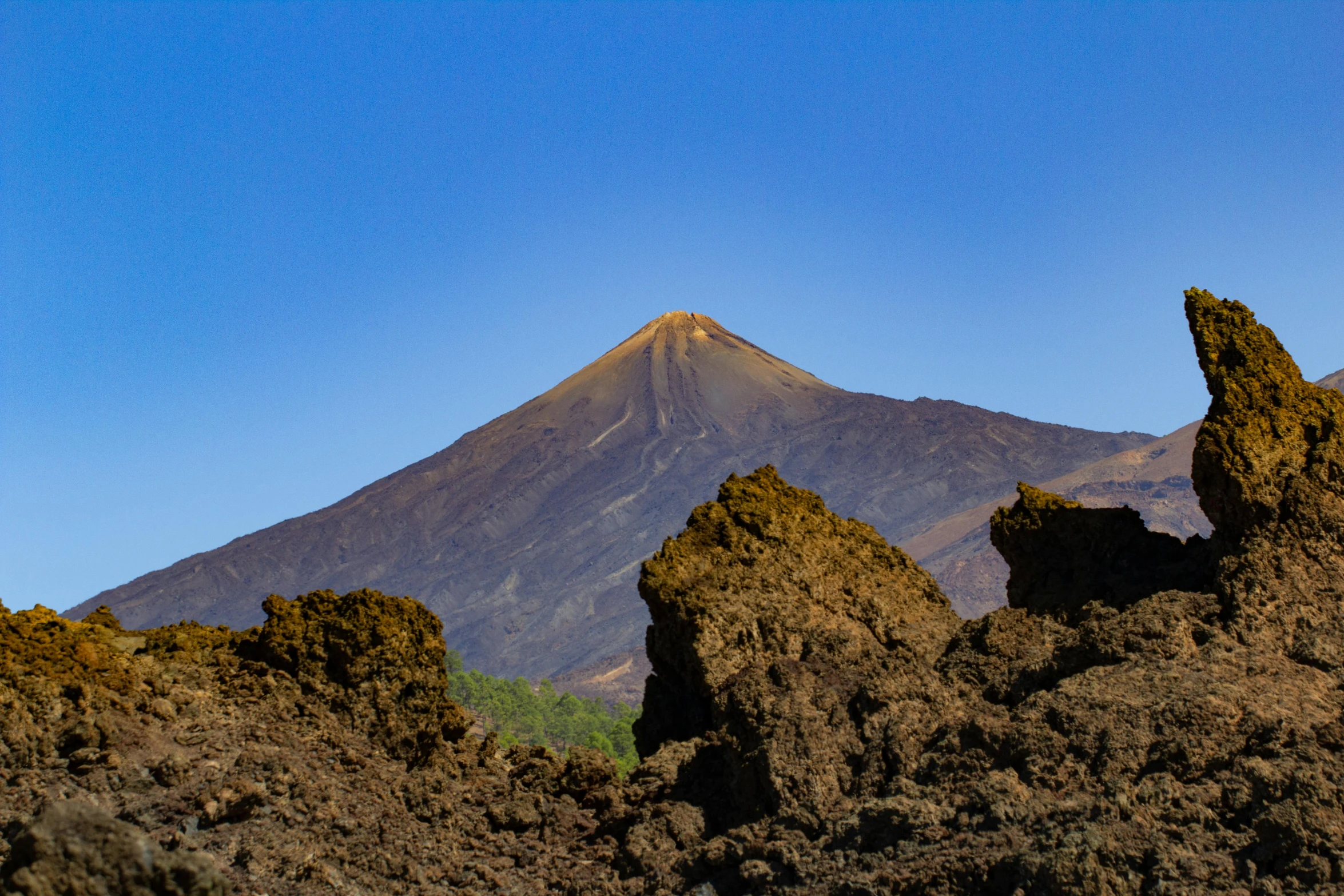 a group of rocks with a mountain in the background, pexels contest winner, hurufiyya, volcanic background, avatar image, brown, corona