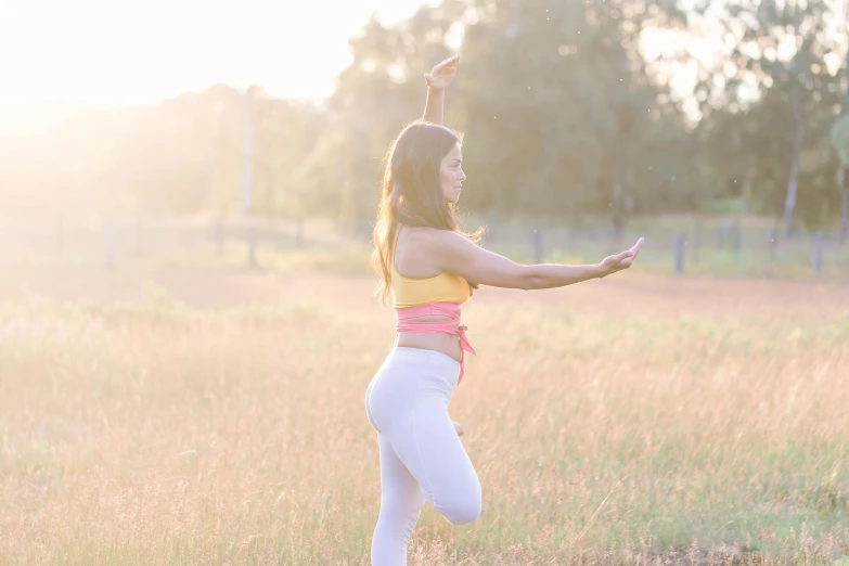 a woman standing in a field holding a frisbee, unsplash, arabesque, marjaryasana and bitilasana, sydney park, background image, soft glow