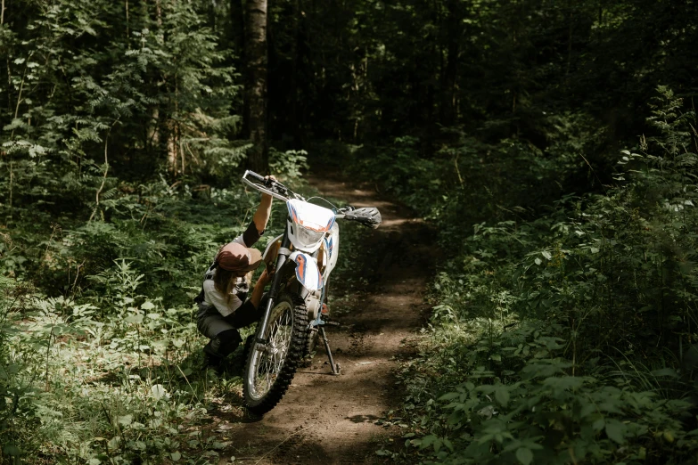 a dirt bike parked on a trail in the woods, by Emma Andijewska, pexels contest winner, figuration libre, white, summer season, avatar image, fun pose