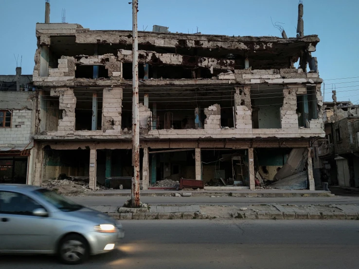 a car that is sitting in front of a building, by Arthur Sarkissian, unsplash, auto-destructive art, iraq nadar, early evening, earthquake destruction, photograph taken in 2 0 2 0