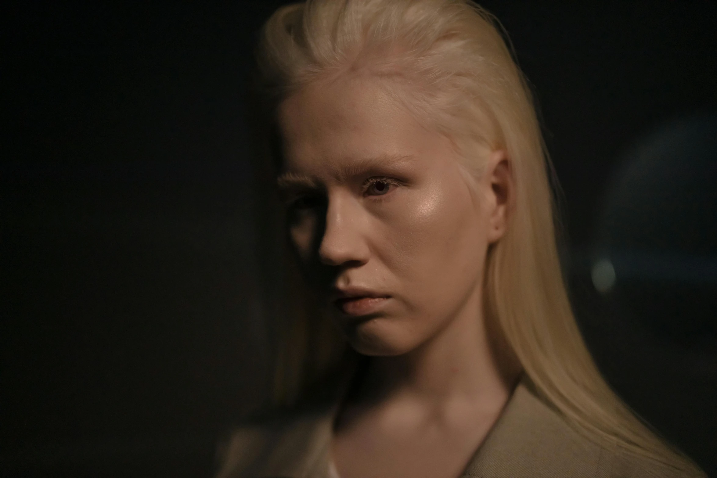 a woman with blonde hair standing in a dark room, intense albino, production still, no eyebrows, julia hetta