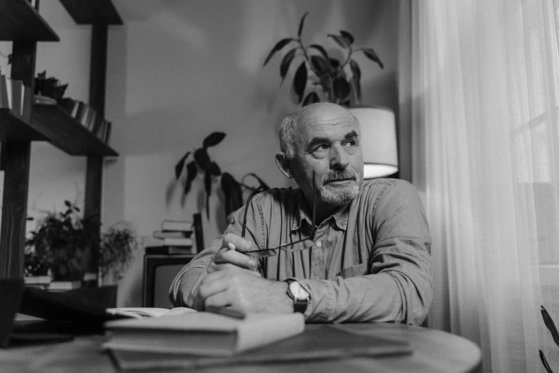 a black and white photo of a man sitting at a table, a portrait, by Jan Konůpek, pexels contest winner, photorealism, koyaanisqatsi, sean connery, at home, author zima blue