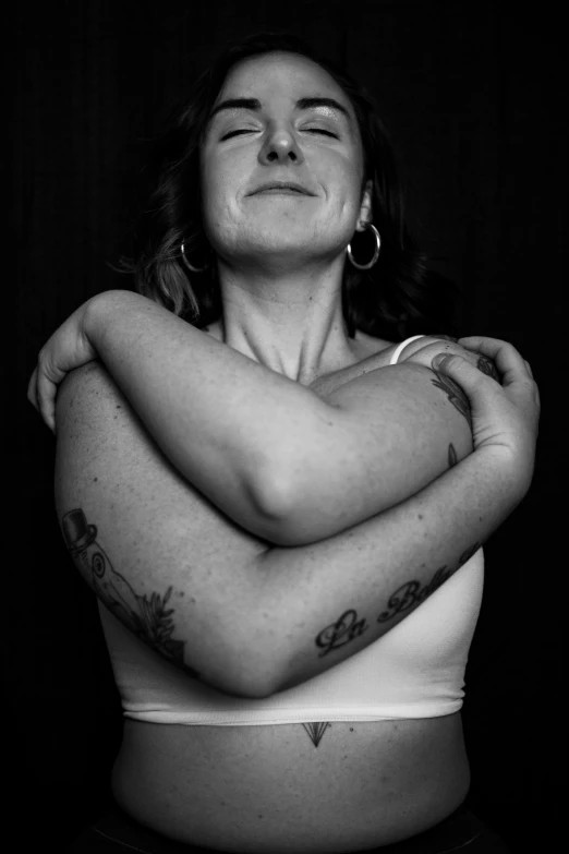 a black and white photo of a woman with tattoos, by Jessie Alexandra Dick, symbolism, hug, stacked image, two arms, low iso