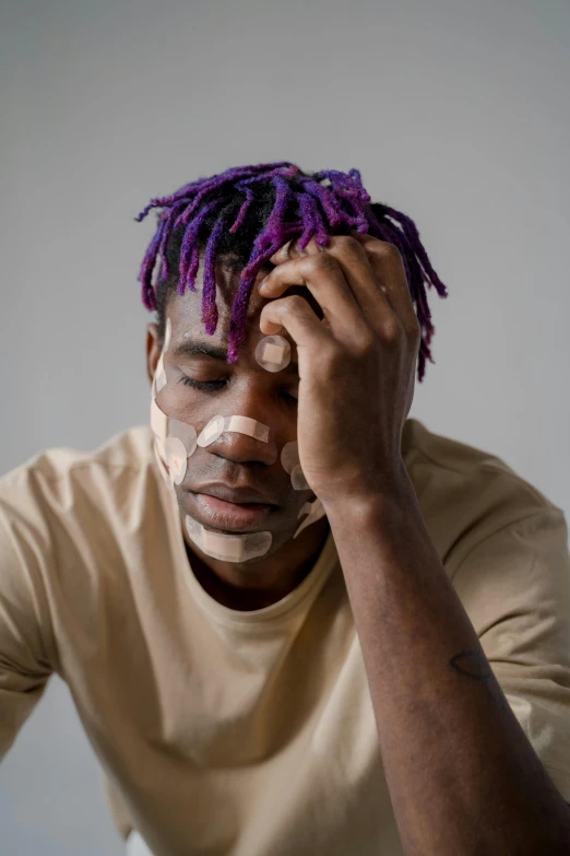 a man with purple dreadlocks sitting at a table, trending on pexels, people crying, swollen muscles, lil uzi vert, portrait of a patchwork boy