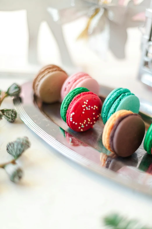 a close up of a plate of macarons on a table, inspired by Rudolf von Alt, holiday season, teal silver red, petite, multiple colors