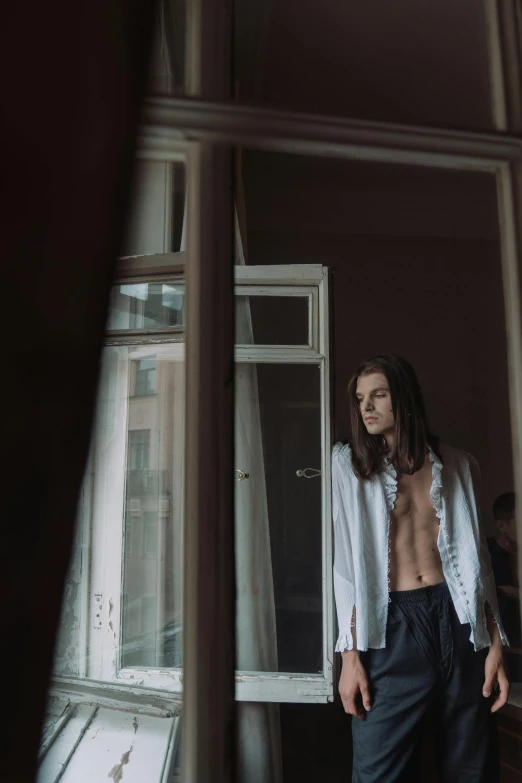 a shirtless man standing in front of a window, inspired by Elsa Bleda, unsplash contest winner, bauhaus, young with long hair, exiting from a wardrobe, wearing a white button up shirt, androgynous vampire