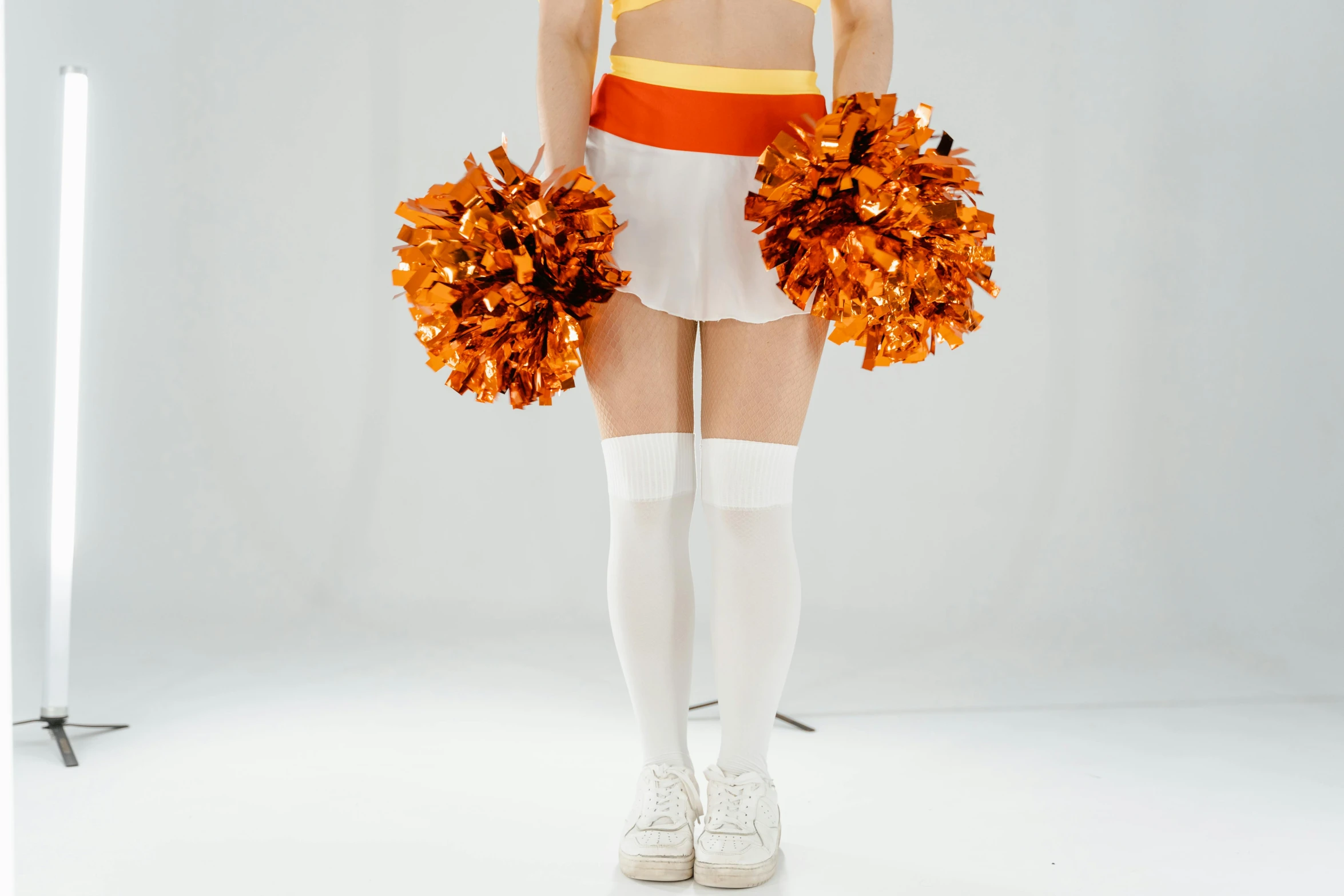 a woman in a cheerleader outfit holding pom poms, pexels, antipodeans, white and orange breastplate, normal legs, leaked footage, cosplay photo