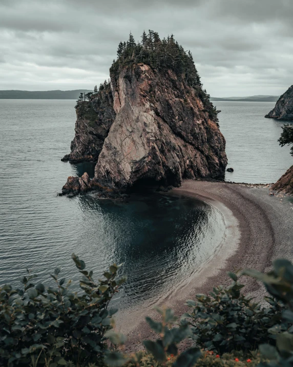 a large rock in the middle of a body of water, hills and ocean, quebec, unsplash photo contest winner, showing curves