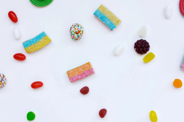 a table topped with lots of different types of candies, trending on pexels, process art, with a white background, jelly - like texture. photograph, rectangle, profile image