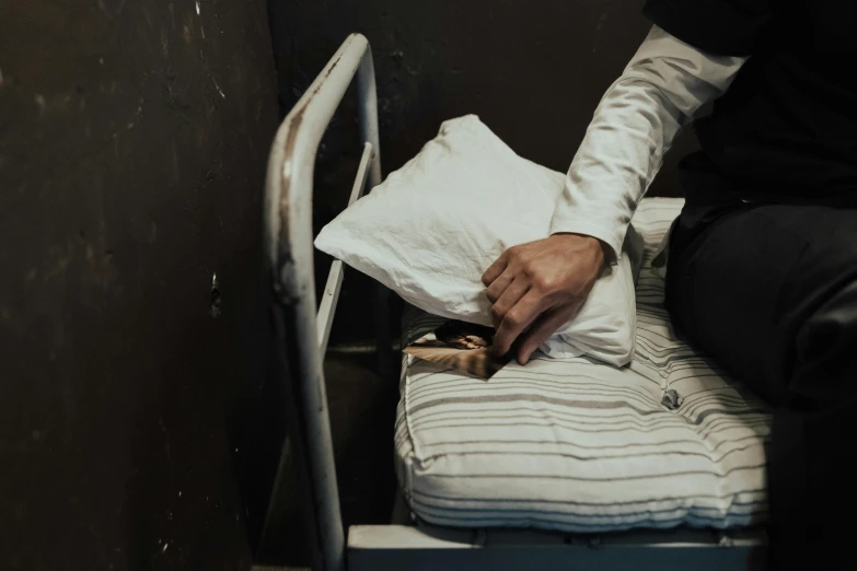 a person sitting on a bed in a room, by Elsa Bleda, arte povera, in prison, holding a stuff, gettyimages, skilled homeless