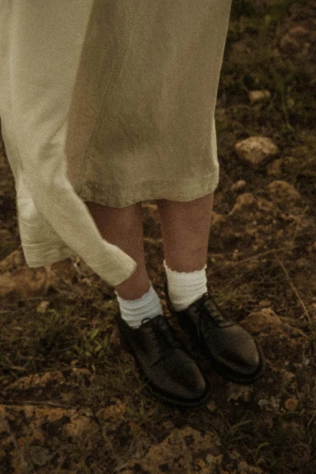 a man standing on top of a grass covered field, an album cover, inspired by Andrew Wyeth, unsplash, wearing skirt and high socks, detail shot, ignant, linen