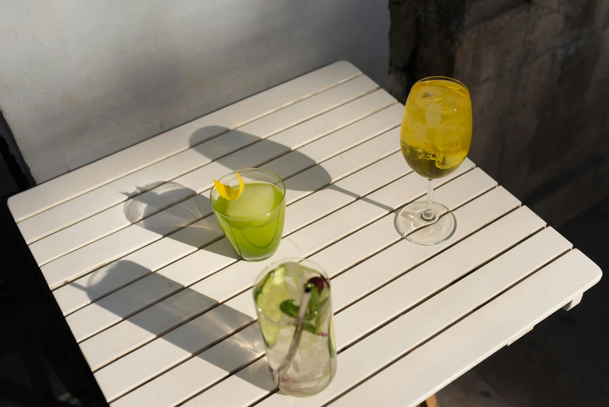 a couple of glasses sitting on top of a table, yellow and greens, deck, mid air shot, background image