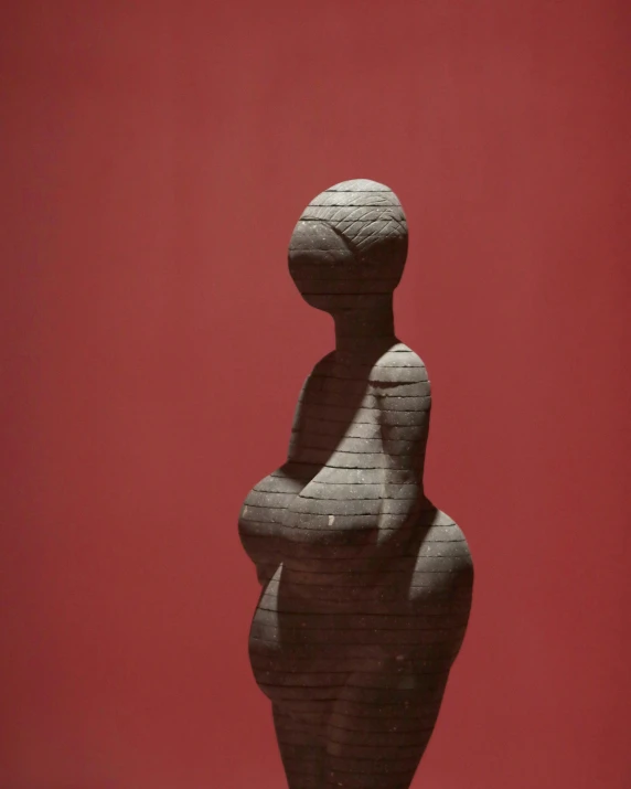 a sculpture of a woman standing in front of a red wall, inspired by Louise Bourgeois, unsplash, feminist art, pregnant, made of cement, brancusi, 2 0 1 0