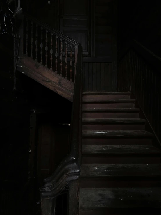 a dark room with a staircase and a chandelier, an album cover, unsplash, jack baker from resident evil 7, background image, wooden stairs, snapchat photo