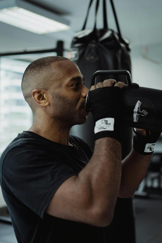 a man punching a punching bag in a gym, a photo, by Sam Charles, happening, hydration, black body, profile image, instagram photo