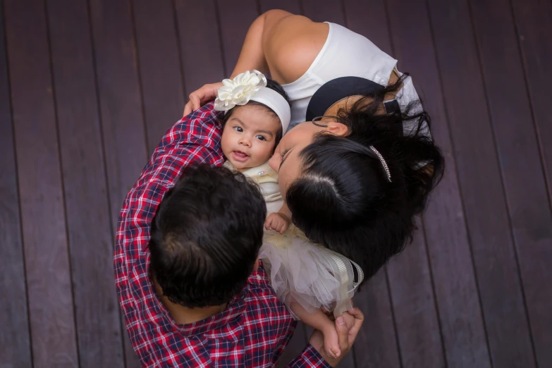 a woman holding a baby in her arms, pexels contest winner, portrait of family of three, taking from above, asian, square