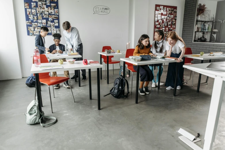 a group of people sitting at desks in a room, pexels contest winner, paris school, white wall coloured workshop, an escape room in a small, profile image, standing on a desk