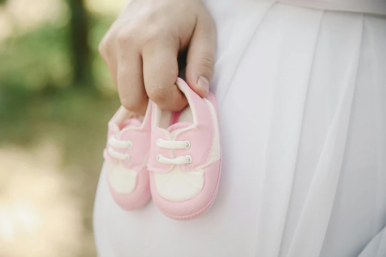 a pregnant woman holding a pair of pink shoes, by Romain brook, pixabay, white and light-pink outfit, children, closeup of an adorable, bumps