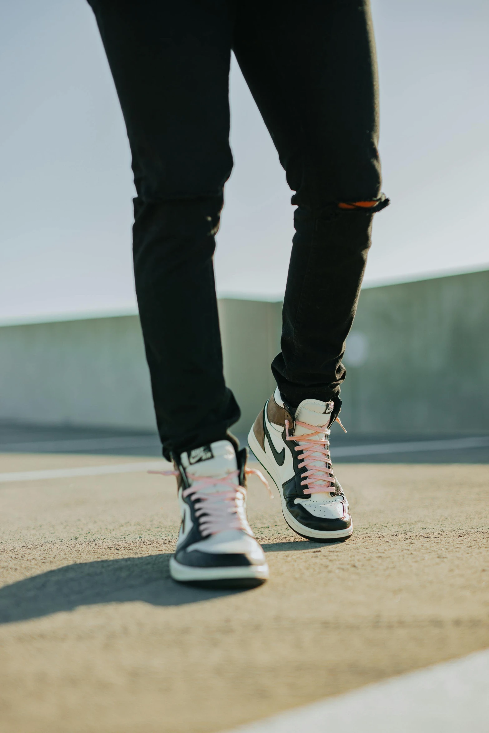 a person standing on a skateboard in a parking lot, air jordan 1 high, black white pastel pink, ( ( ( wearing jeans ) ) ), curated collections