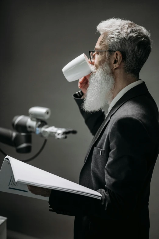 a man with a white beard drinking from a cup, an album cover, unsplash, photorealism, standing microphones, with book of science, boston dynamics, no - text no - logo