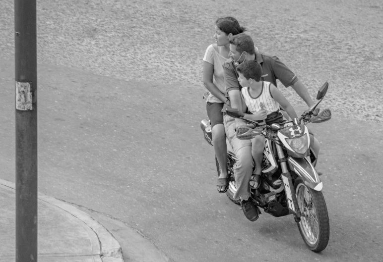 a couple of people riding on the back of a motorcycle, a black and white photo, by Joze Ciuha, flickr, with a kid, streets of salvador, husband wife and son, zoomed in