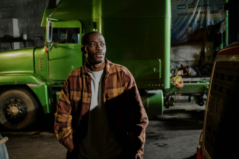 a man standing in front of a green truck, a portrait, by Dan Frazier, pexels contest winner, dave chappelle, ( ( dark skin ) ), brown, broken down