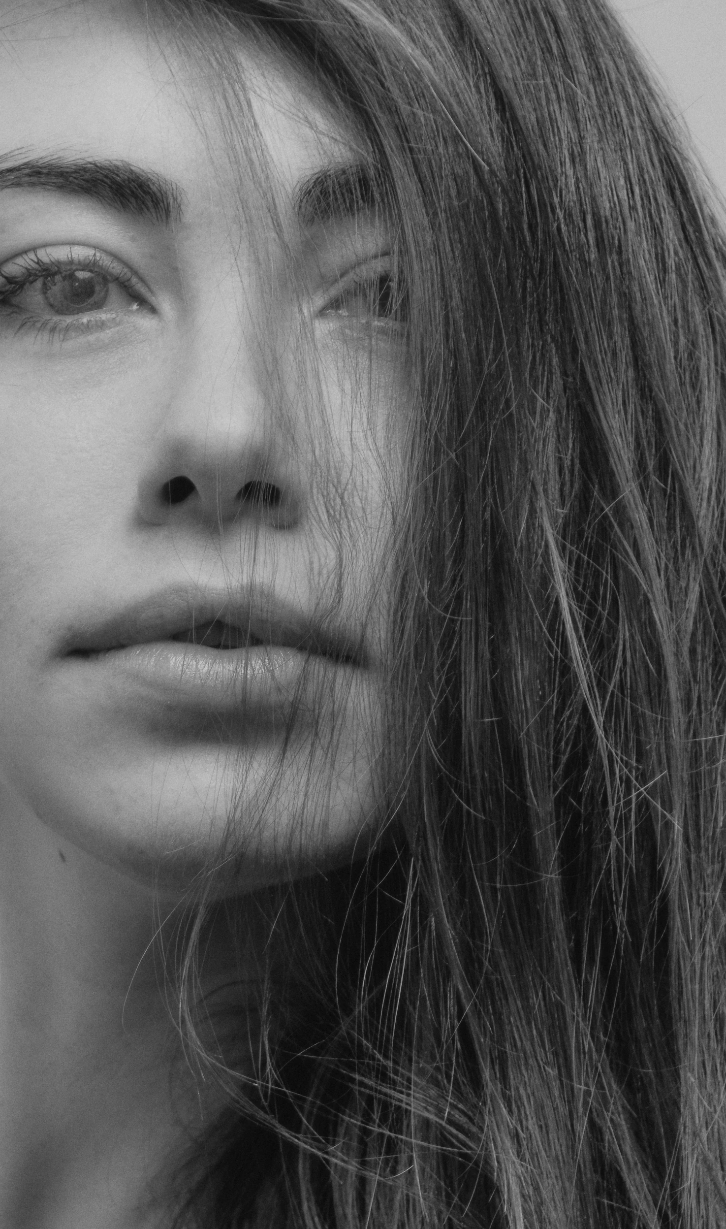 a black and white photo of a woman with long hair, inspired by Ksenia Milicevic, close up of face, noseless, stubble, hair floating in the wind